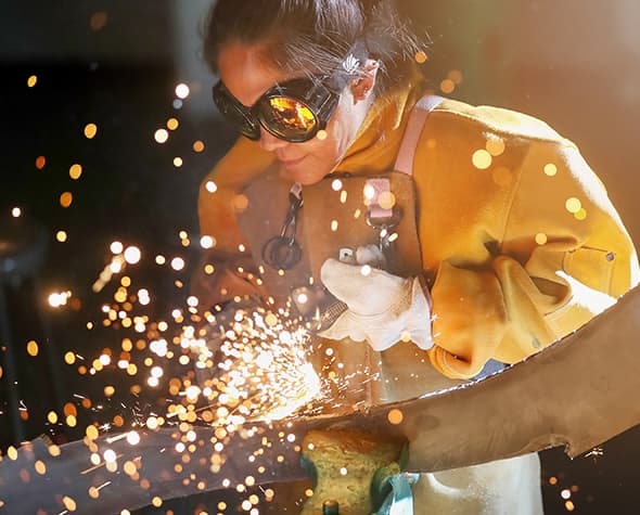 Welder working on metal piece with sparks flying